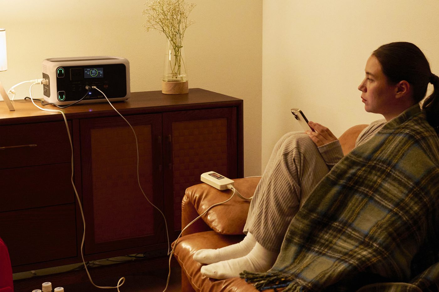 停電の夜、ポータブル電源の電力でともるランプと給電中の本体