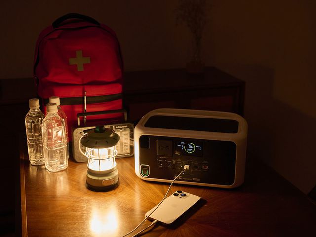 夜、防災リュックとランタンのそばで待機するポータブル電源
