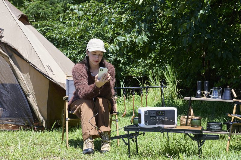 キャンプでスマホを充電しながら過ごす女性とBN-RL410