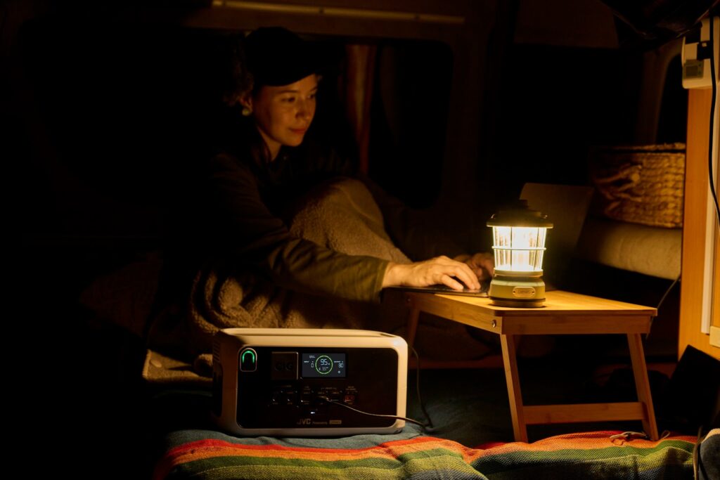 車中泊の夜にポータブル電源で給電したランタンの灯りの下で作業する女性
